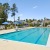 a swimming pool with lounge chairs and umbrellas on a sunny day